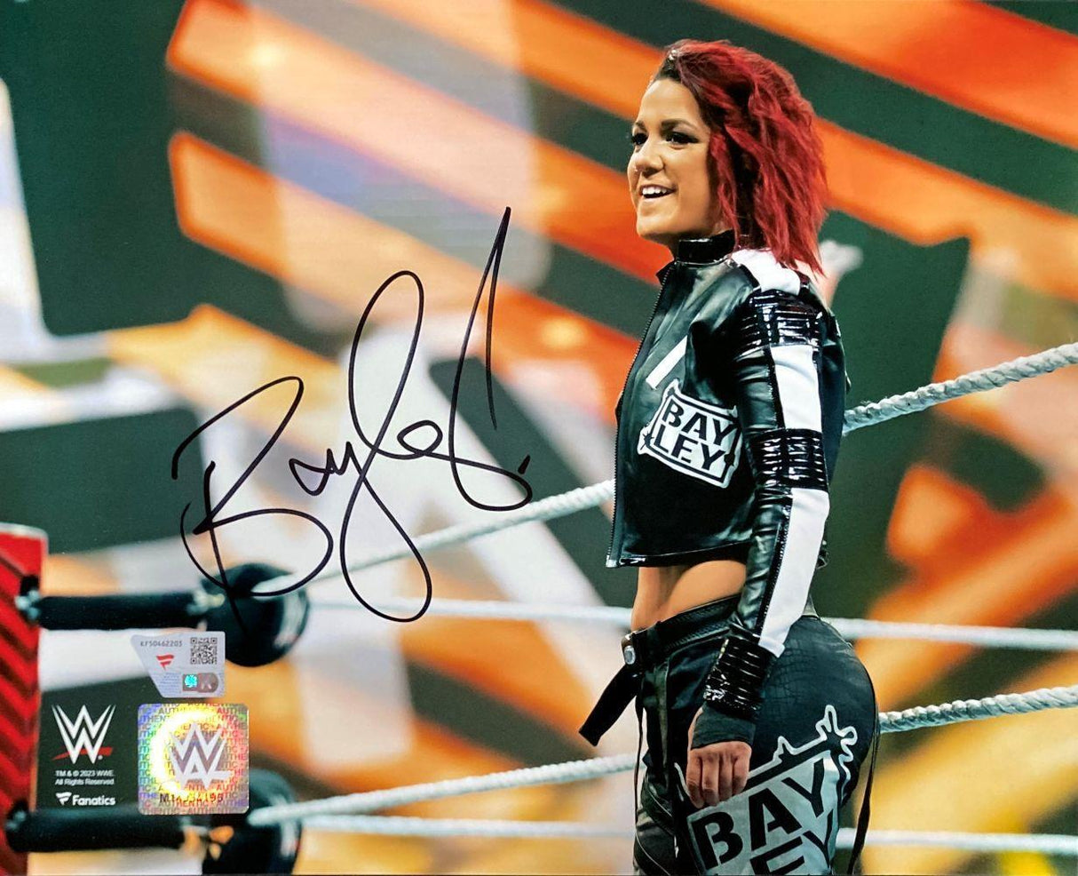 Bayley Signed 8x10 WWE Photo by Sports Integrity features Bayley in a wrestling ring with red hair, wearing black and white attire, smiling confidently. The photo is autographed and shows WWE and Fanatics logos in the corner.