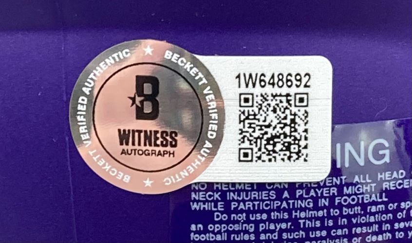 A Beckett Witness Authenticated sticker with QR code and serial number 1W648692 is affixed to the Aaron Jones Signed Minnesota Vikings Mini Speed Helmet BAS w/ Case from Sports Integrity, shown on a purple surface.
