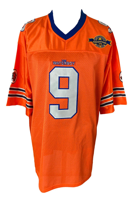 The Sports Integrity Adam Sandler Signed The Waterboy Bobby Boucher Jersey (BAS BF15068) is a bright orange football jersey with blue and white trim, number 9 on the front, and multiple patches including "The Waterboy" on the left chest.