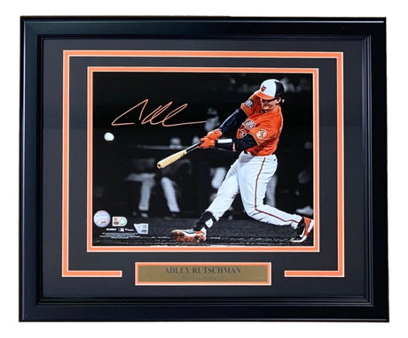 Sports Integrity's Adley Rutschman Signed Framed 11x14 Baltimore Orioles Photo features the player in a white and orange uniform swinging a bat, with his autograph above and a nameplate within an orange and black accented frame.
