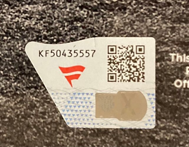 A close-up of a security sticker with a red logo, serial number KF50435557, QR code, and hologram on the Alec Bohm Signed Framed 11x14 Philadelphia Phillies Photo by Sports Integrity.