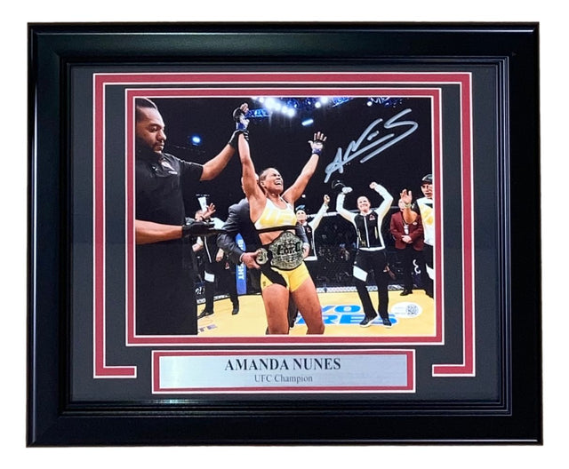 This Sports Integrity Amanda Nunes Signed Framed 8x10 UFC Championship Photo features her celebrating with a belt and includes a JSA QR Hologram, plus a silver plaque inscribed “UFC Champion” below the image.