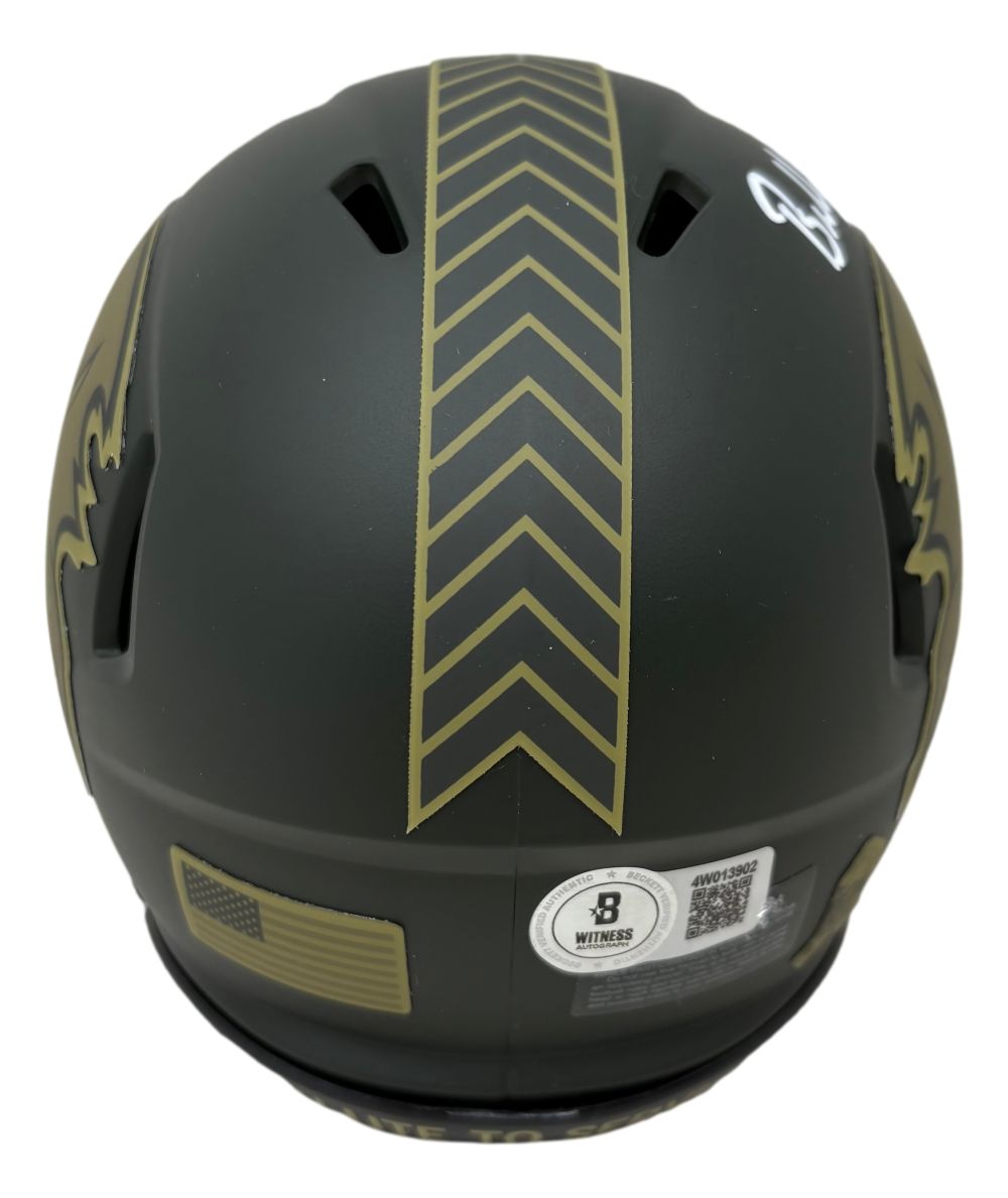 A Baker Mayfield Signed Buccaneers Salute To Service Mini Speed Helmet by Sports Integrity, black with gold chevron stripes and a fleur-de-lis design, viewed from the back with stickers including a QR code and certification label.