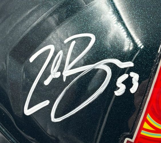 A close-up of the Zack Baun Signed Eagles FS Super Bowl 59 Speed Replica Helmet by Sports Integrity shows a bold white autograph with the number 53 on its glossy dark green surface and part of a colorful sticker on the right edge.