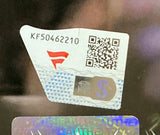 A close-up of a security sticker on the Sports Integrity Bayley Signed Framed 8x10 WWE Wrestlemania XL Photo Fanatics displays code KF50462210, a QR code, a red logo, blue S, holographic features, and partial "AUTHENTIC" text.