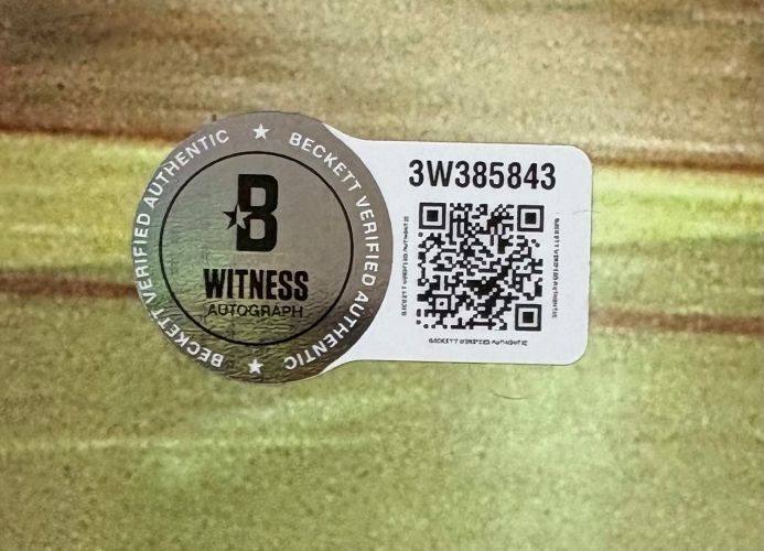 A Beckett Verified Authentic QR code sticker with serial number 3W385843 and Witness Autograph is on a flat, light greenish-brown surface of the Larry Bird Magic Johnson Dual Signed 16x20 Celtics Lakers Photo by Sports Integrity.