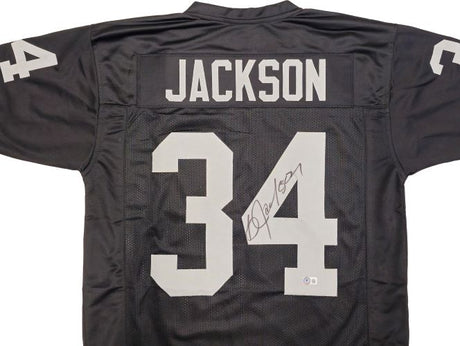 The Sports Integrity Bo Jackson Oakland Signed Black Football Jersey BAS features “JACKSON” and the number 34 in white on the back and sleeves, with Bo Jackson’s signature in black ink on the number.