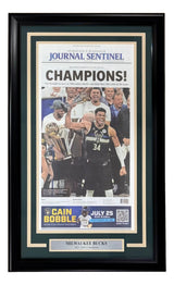 The Sports Integrity Milwaukee Bucks Framed 2021 NBA Champions Milwaukee Journal Sentinel Newspaper displays the “CHAMPIONS!” front page, with Bucks players celebrating their 2021 victory and a plaque reading “Milwaukee Bucks 2021 NBA Champions.”.