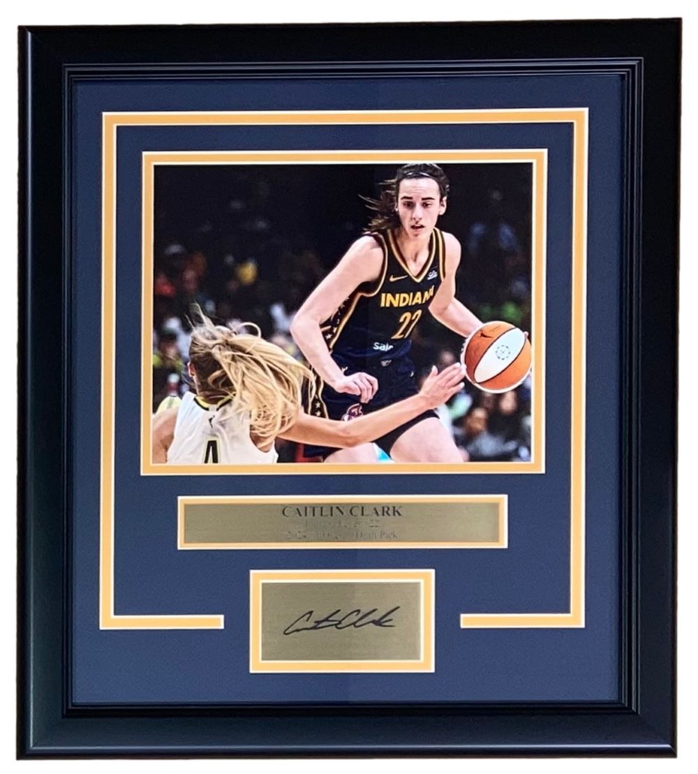 The Sports Integrity Caitlin Clark Framed 8x10 Indiana Fever Crossover Photo features her in a black jersey holding a basketball, with a laser engraved autograph and nameplate displayed below the image.