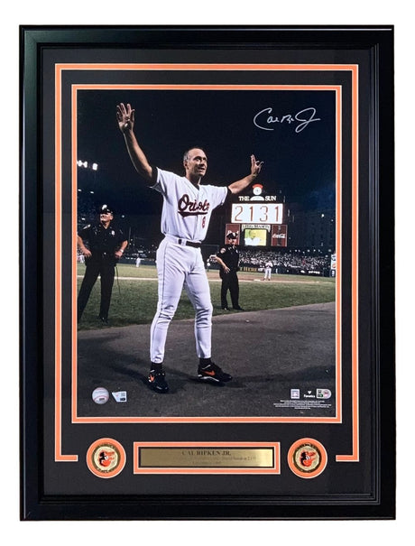 The Sports Integrity Cal Ripken Jr Signed Framed 16x20 Orioles Game 2131 Photo features him in uniform with arms raised, autograph, team logos, and a nameplate—all showcased in a collectible display by Fanatics.