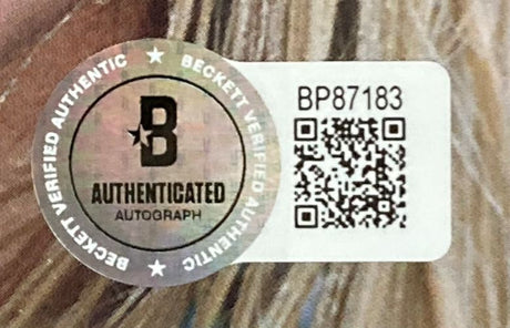 A Beckett Authenticated Autograph sticker with QR code, serial BP87183, and silver "Beckett Verified Authentic" seal is attached to the Sports Integrity Camila Cabello Signed Framed C,XOXO CD Insert BAS on a light brown textured background.