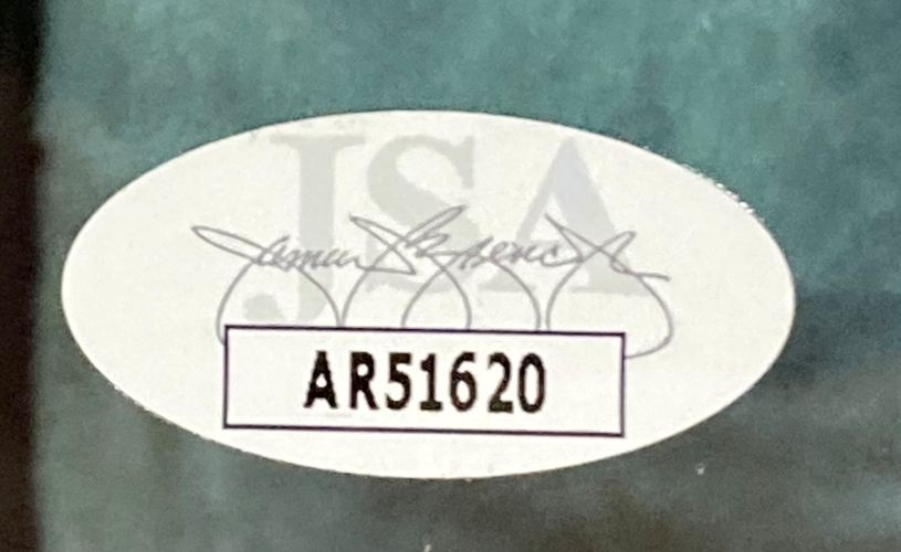 Sports Integrity Carl Weathers signed framed 8x10 Predator photo features an oval JSA sticker with a faded logo, black signature, and bold black code “AR51620” inside a rectangle on a greenish background.