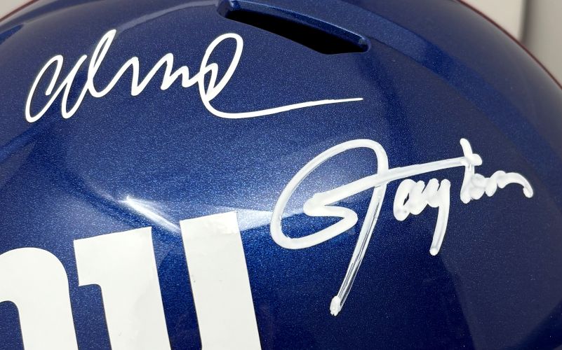 A close-up of the Sports Integrity Lawrence Taylor Abdul Carter Signed New York Giants FS Replica Speed Helmet, showcasing two white autographs and part of a white number on the left side.
