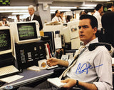 A man in business attire sits at a busy office desk with retro monitors, phones, and a cup with a Lakers logo, featuring the Sports Integrity Charlie Sheen Signed 11x14 Wall Street Photo with PSA/DNA Hologram.