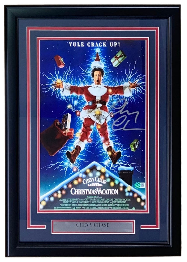 The Sports Integrity Chevy Chase Signed Framed 11x17 Lampoon’s Christmas Vacation Photo BAS features the iconic scene with a man shocked by Christmas lights, “YULE CRACK UP!” above, and a plaque with Chevy Chase’s name.