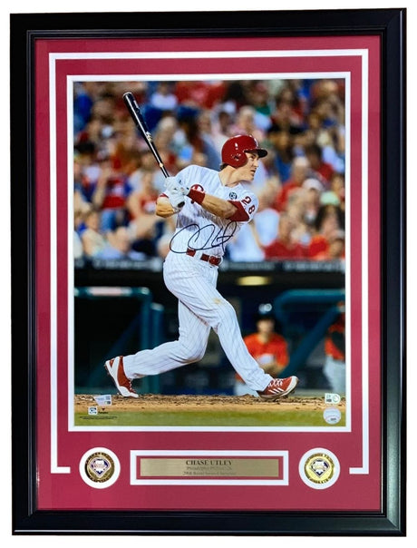 A Chase Utley Signed Framed 16x20 Philadelphia Phillies Photo by Sports Integrity, featuring Utley in a white pinstripe uniform swinging a bat, with two commemorative patches and a nameplate included at the bottom of the frame.