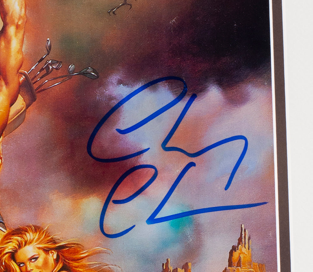 A close-up of the Chevy Chase Signed Framed 11x17 National Lampoon's Vacation Photo by Sports Integrity, featuring a large blue autograph, a person's arm with arrows on the left, and part of a woman's face and hair in the bottom left corner.