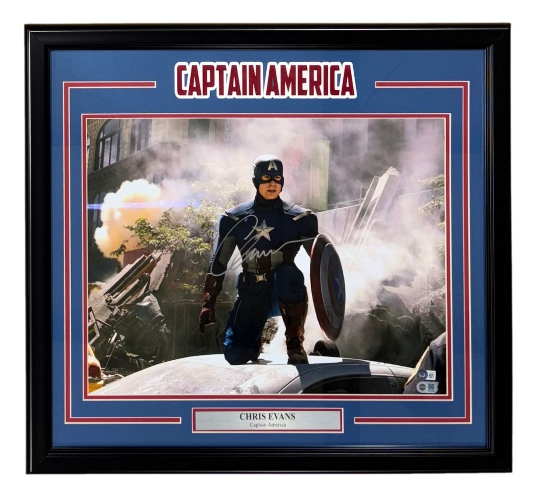 The Sports Integrity Chris Evans Signed Framed 16x20 Captain America Kneel Photo 2 BAS LOA features Chris Evans as Captain America kneeling on a damaged car amidst smoke and debris, highlighted by an explosion in the background.