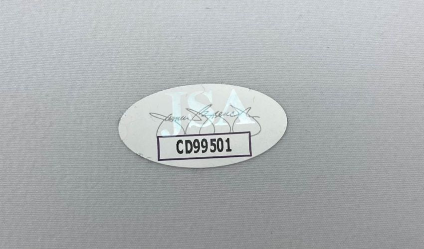 A Coco Gauff Signed New Balance Adjustable Hat by Sports Integrity features an oval JSA authentication sticker with a signature, the letters JSA, and code CD99501 on a light gray surface.