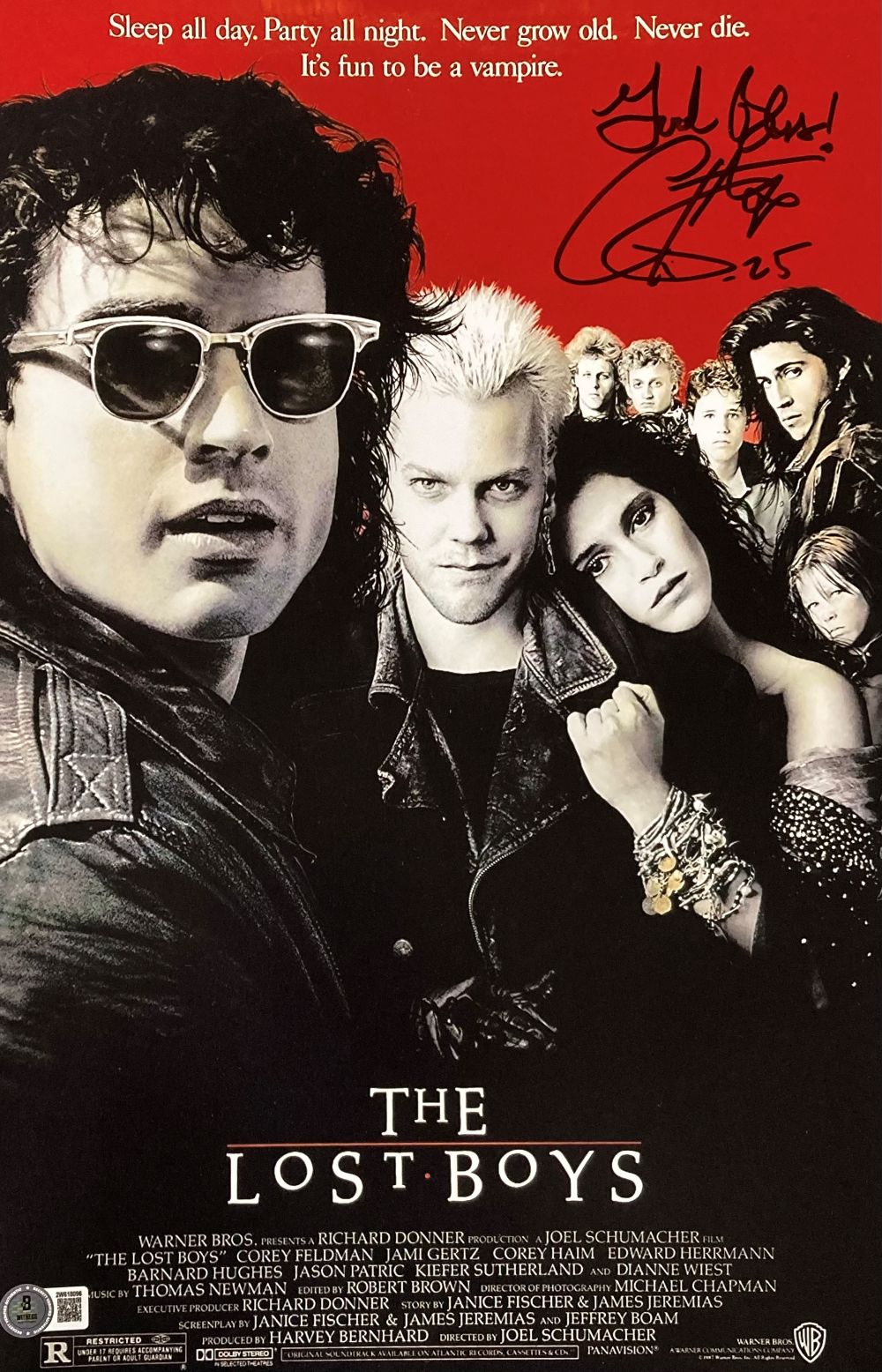 A group of stylish young vampires stands against a red background with “The Lost Boys” title. Featured: Corey Feldman Signed 11x17 Photo "God Bless" Inscribed (Sports Integrity, BAS).