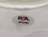 A close-up of the Sports Integrity John Daly Signed White Daly Adjustable Hat's fabric label, featuring an oval PSA/DNA sticker in red and blue with code AP53385.