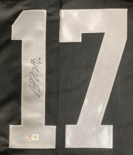A large white number 17, signed in black marker and featuring an authentication sticker, is stitched onto the black mesh of the Davante Adams Oakland Signed Black Football Jersey by Sports Integrity.