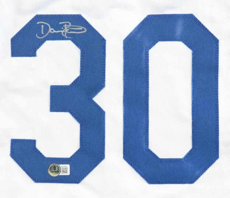 The Sports Integrity Dave Roberts Los Angeles Signed White Baseball Jersey BAS features a large blue 30 with a silver autograph on the upper left of the 3 and an authentication sticker at its base.