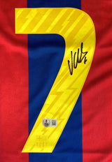 The Sports Integrity David Villa Signed Barcelona Nike Soccer Jersey BAS features a yellow number 7 with lightning bolt pattern and signature on a red and blue striped jersey, plus an authenticity sticker and team badge at the bottom.