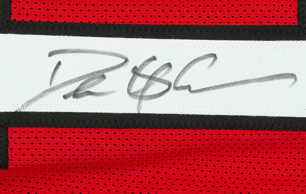 A Deion Sanders Signed Custom Red Pro Style Football Jersey by Sports Integrity displays his autograph in black marker on the white stripe, with red, white, and black mesh fabric that adds authentic athletic detail to this unique memorabilia.