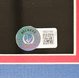 A close-up of a Beckett Witnessed holographic sticker and barcode label (code 1W227369) on the Sports Integrity Tommy Devito Signed Framed 11x14 New York Giants Spotlight Photo BAS ITP, with a black background bordered in red and white.