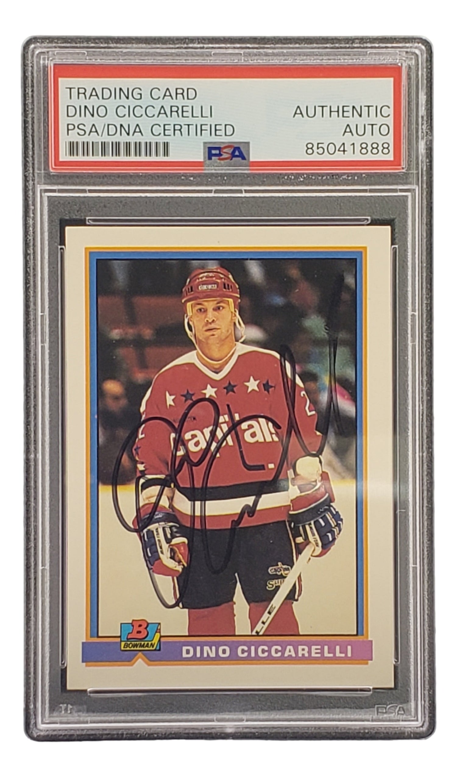 The Sports Integrity Dino Ciccarelli Signed 1991 Bowman #302 Washington Capitals Hockey Card is PSA/DNA certified and features Ciccarelli in a red Capitals jersey on the ice.
