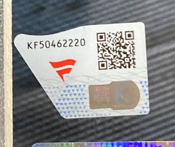 A close-up of a security sticker on the Sports Integrity The Dudley Boyz Signed Framed 16x20 WWE Photo Fanatics, showing the code KF50462220, QR code, red logo, and an 'R' hologram against a patterned background.