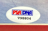 A close-up of a white oval PSA/DNA authentication sticker with a red and blue logo and code V98804 on an Edgar Mitchell Signed Framed 16x20 NASA Apollo 14 Photo by Sports Integrity.