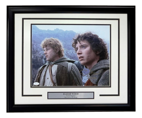 Elijah Wood Signed Framed 11x14 Lord Of The Rings Photo w/ Samwise by Sports Integrity features both characters in medieval attire outdoors with mountain scenery, complete with JSA Hologram authenticity.