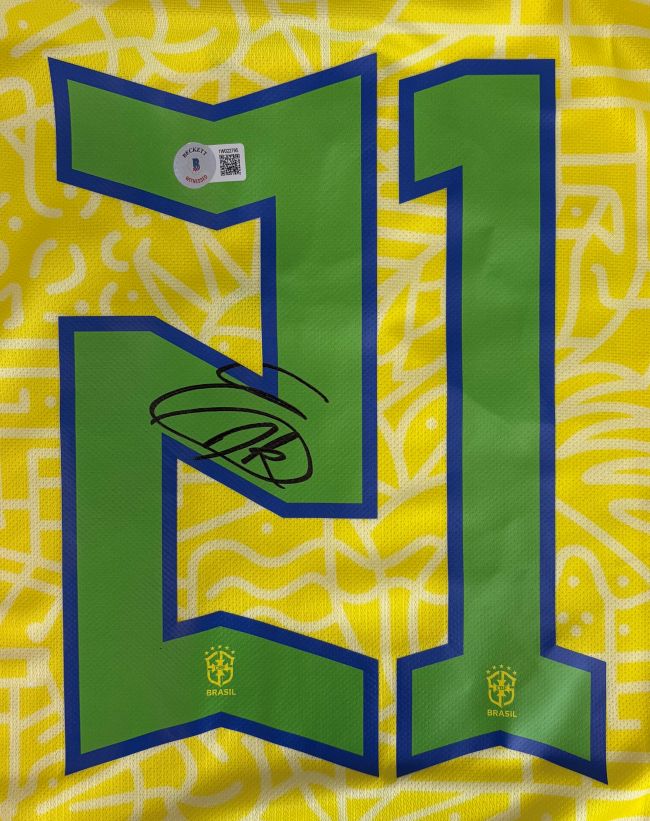The Endrick Signed Brazil Nike Soccer Jersey by Sports Integrity features yellow and green colors, bold blue and green number 21, two Brazil logos, a black autograph on the left digit, and an authenticity sticker above the number.