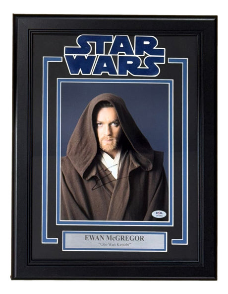 Ewan McGregor signed and framed 8x10 Star Wars Obi-Wan Kenobi photo by Sports Integrity, featuring a visible autograph, PSA/DNA hologram, Star Wars logo, and plaque reading “Ewan McGregor ‘Obi-Wan Kenobi’.”.