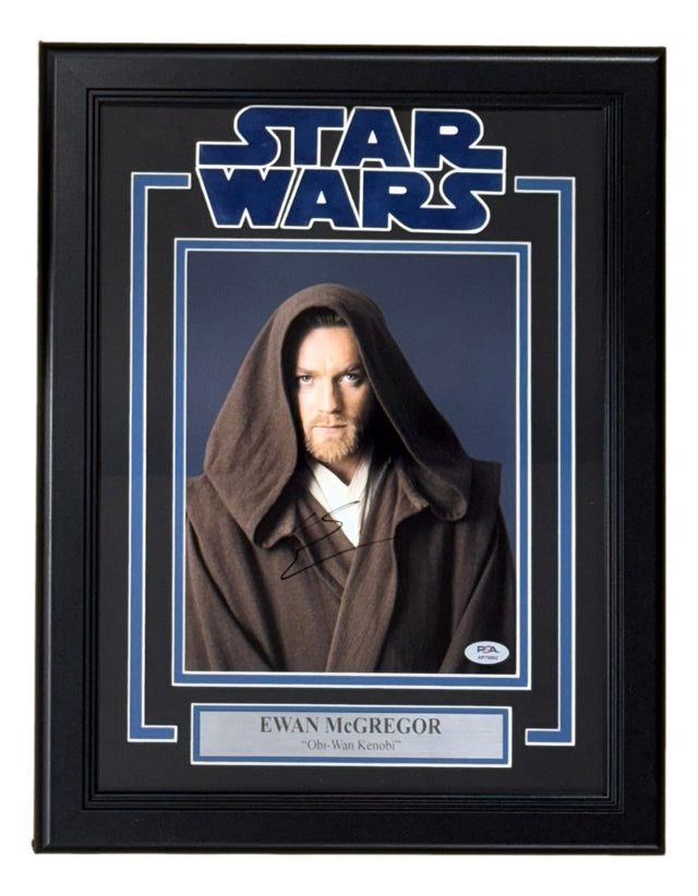 Ewan McGregor signed and framed 8x10 Star Wars Obi-Wan Kenobi photo by Sports Integrity, featuring a visible autograph, PSA/DNA hologram, Star Wars logo, and plaque reading “Ewan McGregor ‘Obi-Wan Kenobi’.”.