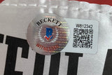 Close-up of a Beckett Witnessed Authentication sticker on a Floyd Mayweather Jr Signed Red Everlast Right Hand Boxing Glove by Sports Integrity, showing the holographic seal, blue and red logo, "WITNESSED," QR code, and ID “W812342.”.