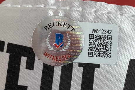 Close-up of a Beckett Witnessed Authentication sticker on a Floyd Mayweather Jr Signed Red Everlast Right Hand Boxing Glove by Sports Integrity, showing the holographic seal, blue and red logo, "WITNESSED," QR code, and ID “W812342.”.