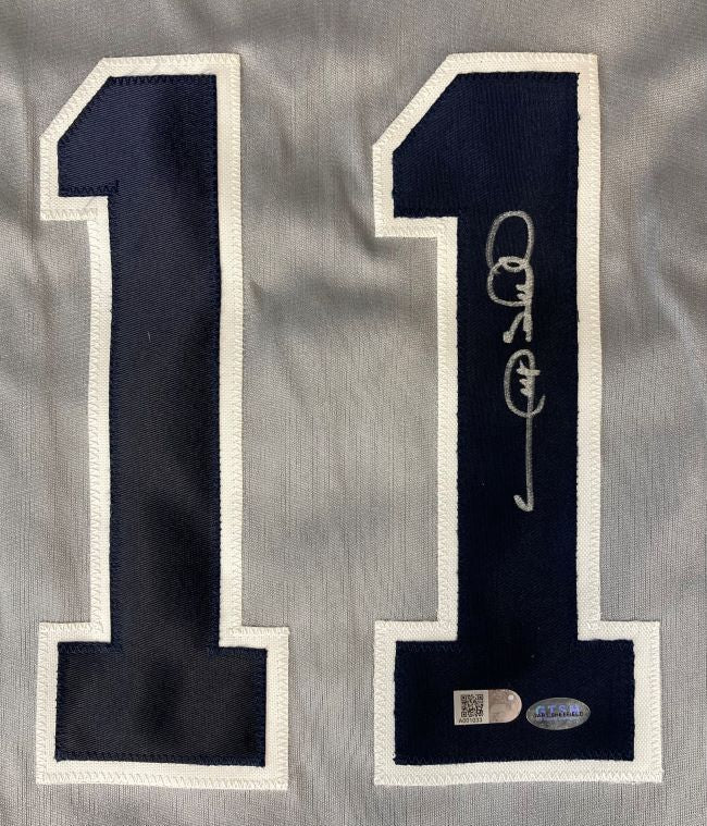 A close-up of the number 11 in dark blue with white trim on gray fabric from the Gary Sheffield New York Signed Gray Baseball Jersey by Sports Integrity, showing a silver autograph and two authentication stickers on the lower right digit.
