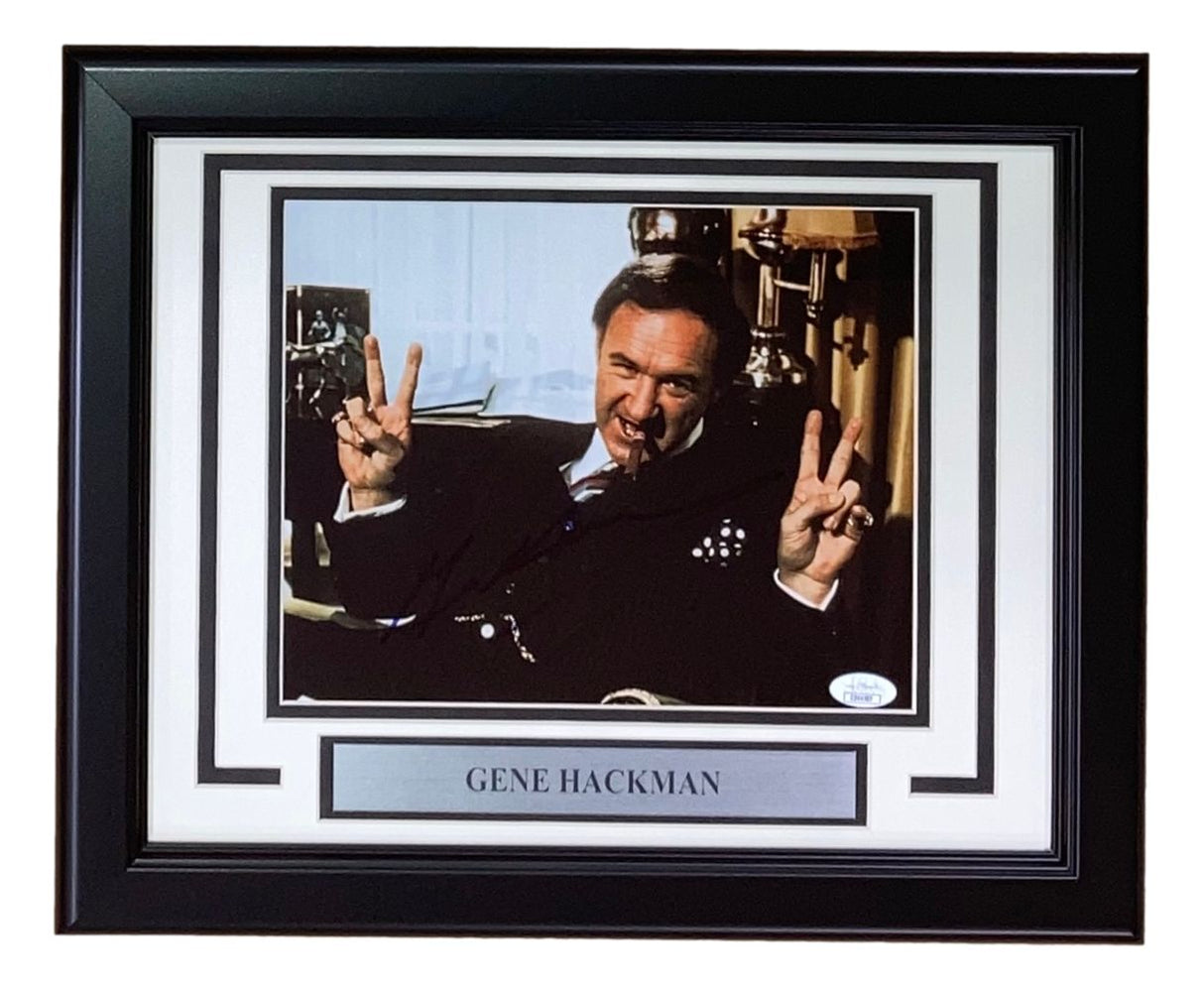 A framed 8x10 photo of Gene Hackman from Sports Integrity, featuring him smiling with a peace sign. Includes a plaque reading GENE HACKMAN and comes signed with JSA authentication.