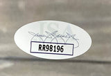 An oval JSA hologram with a faint signature and bold code RR98196 is affixed to the Giannis Antetokounmpo Signed Framed 11x14 Milwaukee Bucks Photo from Sports Integrity; the sticker sits inside a white box on a blurred gray background.