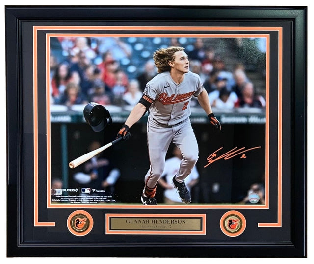The Sports Integrity Gunnar Henderson Signed Framed 16x20 Baltimore Orioles Photo features Henderson running in a gray uniform, helmet and bat airborne. Includes his autograph, two Orioles logos, and a Gunnar Henderson nameplate.