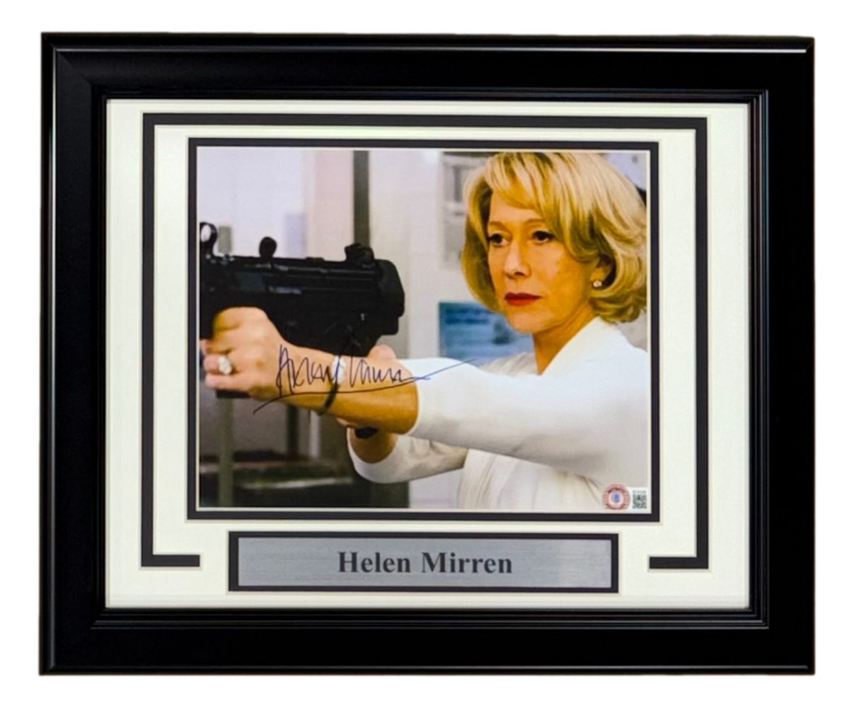 Sports Integrity Helen Mirren Signed Framed 8x10 Red Photo BAS features a framed, autographed photo of Helen Mirren in white aiming a gun, with her name displayed on a plaque below.