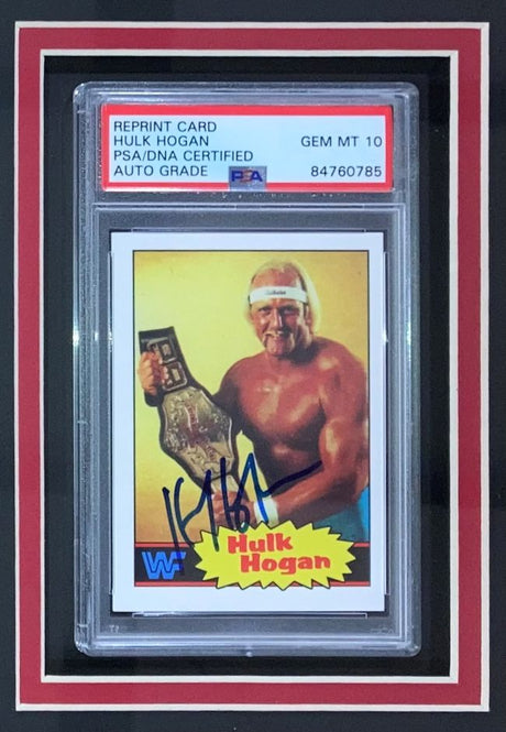The Sports Integrity Hulk Hogan Signed Framed Reprint 1985 Topps #1 Rookie Card features a shirtless Hogan holding a championship belt, encased with a red border and graded PSA Auto 10.