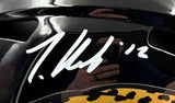 A close-up of a Travis Hunter signed Jacksonville Jaguars FS Speed Replica Helmet by Sports Integrity, featuring the number 12 and a white signature. The shiny surface reflects the person taking the photo. Includes BAS authentication and display case.