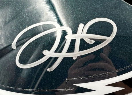 A close-up of a Jalen Hurts Signed Philadelphia Eagles FS Speed Replica Helmet by Sports Integrity, featuring a bold white autograph. The glossy surface faintly reflects a hand holding a camera. Includes Fanatics case.