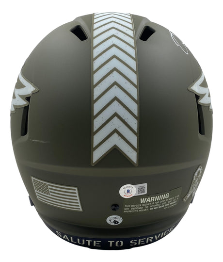 The Sports Integrity Jalen Hurts Signed Eagles FS Salute To Service Speed Replica Helmet BAS+Hurts features a matte army green finish, chevron stripes, American flag decal, warning label, and "SALUTE TO SERVICE" on the lower edge.