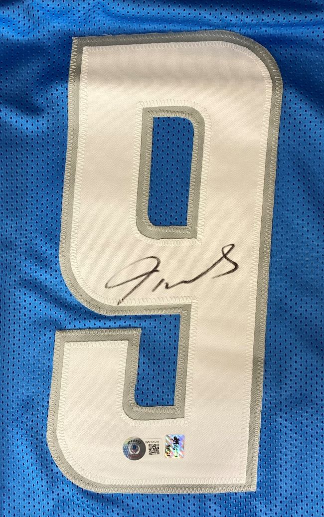 Close-up of a Jameson Williams Detroit Signed Light Blue Football Jersey by Sports Integrity, featuring a large white number 9 with signature and two authentication stickers near the bottom.