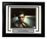 A Sports Integrity framed 8x10 photo of Jeff Goldblum from Jurassic Park, signed and authenticated by BAS, features him in sunglasses and a black leather jacket with dramatic lighting.